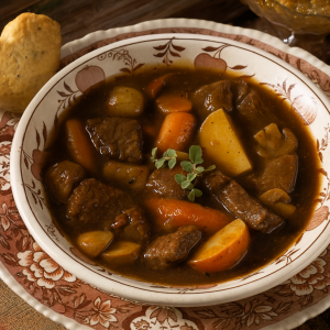Traditional German beef stew served in a rustic bowl with carrots, potatoes, and mushrooms in a rich red wine sauce.