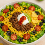 Taco Salad Tex-Mex Style with seasoned minced beef, lettuce, cherry tomatoes, olives, corn, cheddar, and tortilla chips